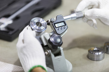 operator inspection automotive part by micrometer