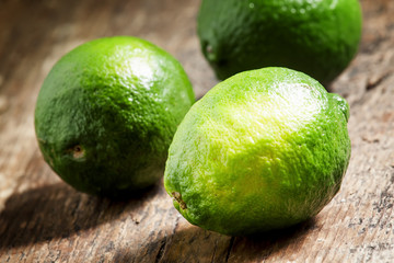 Fresh limes on an old wooden table, selective focus