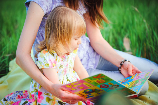 Mom and daughter reading a book in the park