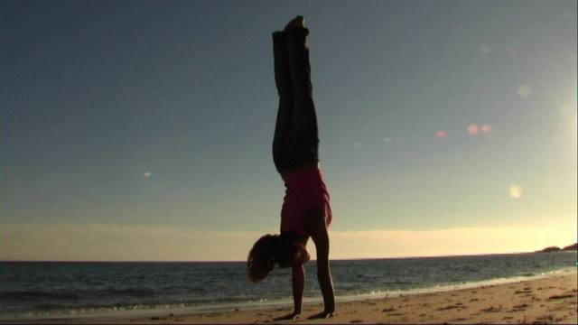 Woman on beach doing acrobatics