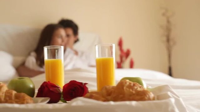 Pan shot of couple in bed with breakfast