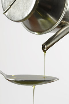 Filling up a tablespoon of extra-virgin olive oil