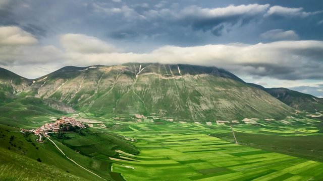 Dusk over green field in mountain at spring, Castelluccio, Italy
