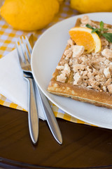 Waffles with meringue, lemon curls and orange slices 
