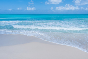 Turquoise waters and gentle waves on a white sand Caribbean beach.