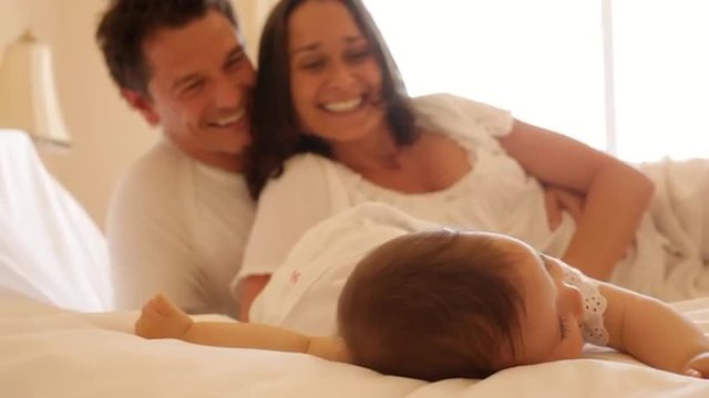 Family and baby on bed