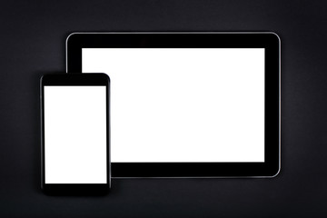 Tablet and smartphone on dark office desk.