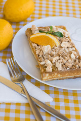 Waffles with meringue, lemon curls and orange slices