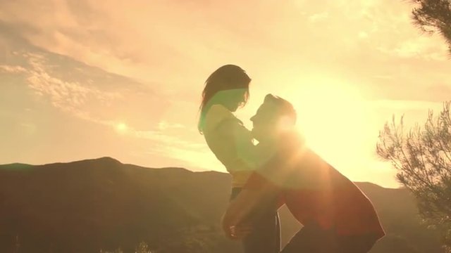 Slow motion shot of young couple dancing and hugging overlooking mountain.