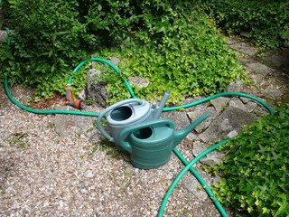 garden watering cans and watering hose, in a garden