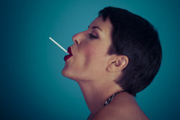 Obraz premium Sweet, happy young woman with lollypop in her mouth on blue