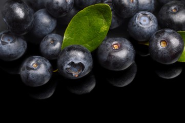 Several whole blueberries with leaves isolated on black corner