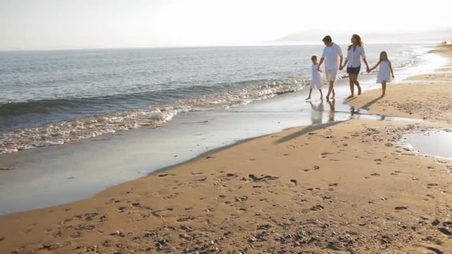pan shot of family walking towards camera on beach