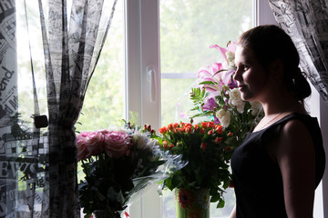 The girl thought for a moment, standing near the window with flowers