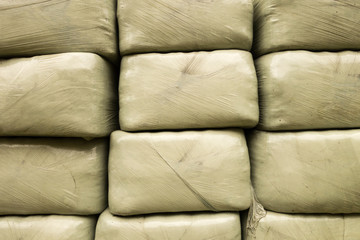 Stacked bales of harvested hay wrapped with plastic film on an early morning at the beginning of...
