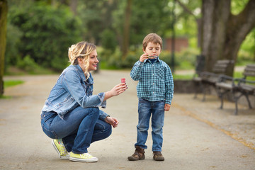 Mother and son playing in a park blowing soap bubbles