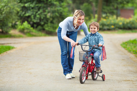 Little boy learning to ride a bicycle with his mother’s help
