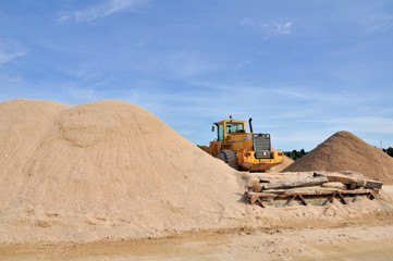 Bulldozer entre des tas de sable sous un beau ciel bleu