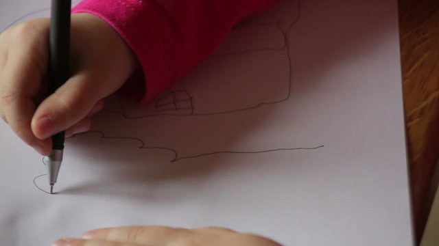 hand of a little girl draws a tree on paper
