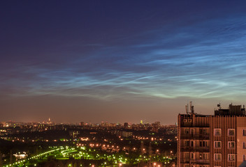 A rare atmospheric phenomenon Noctilucent clouds over the night city 