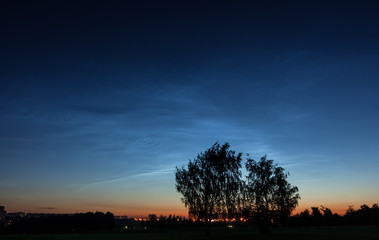 A rare atmospheric phenomenon Noctilucent clouds over the night city 