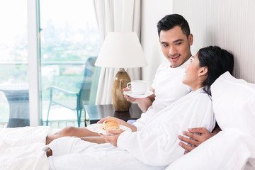 Asian couple lounging in bed at morning