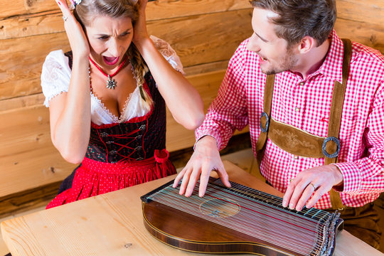 Mann spielt schlecht auf Zither in Bergh&uuml;tte