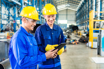 Two workers in production plant as team
