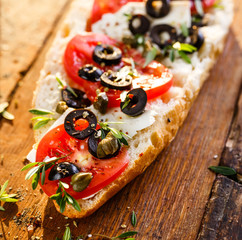 Sandwich with feta cheese, tomatoes, black olives, capers and fresh herbs