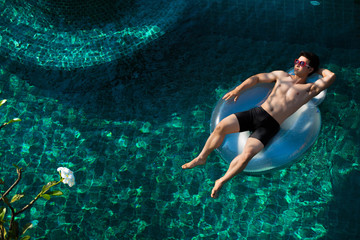Men relaxing at a resort in the pool. He lay on the ring and ver