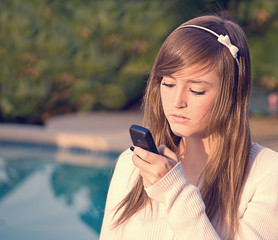 Pretty Teen Girl Looking Unhappily at Cell Phone