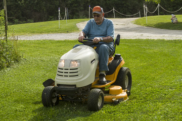 Senior Citizen Cutting Grass On A Riding Lawnmower