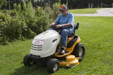 Older Male Mowing Grass With His Riding Mower