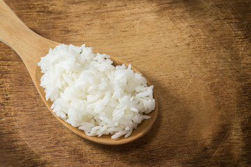 wooden spoon with white boiled rice on wood background