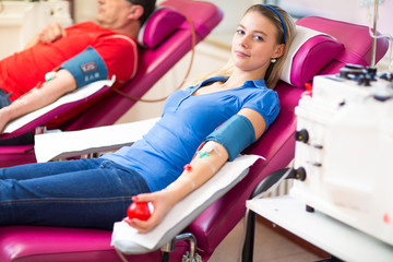 Young woman giving blood in a modern hospital - obrazy, fototapety, plakaty
