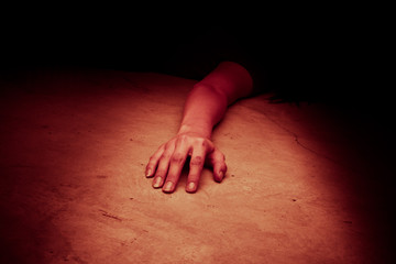 The dead woman's body. Focus on hand, red tone color processed