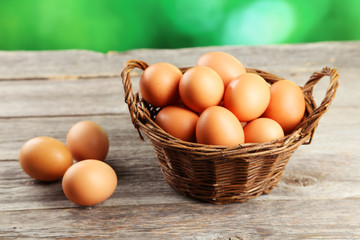 Chicken eggs in basket on grey wooden background