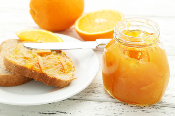 Bread with orange jam on white wooden background