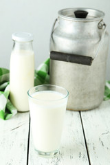 Can and glass of milk on white wooden background