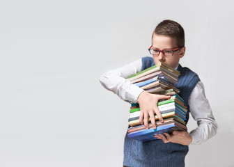 Schoolboy in glasses with stack of books