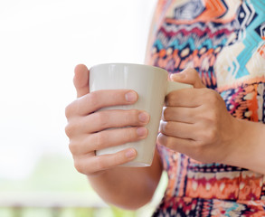 Young woman enjoying a mug of beverage.