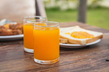 fresh orange juice with sliced bread background on wooden table