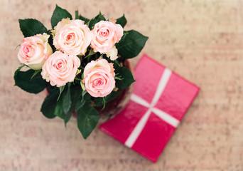 Vase with roses and gift with ribbon