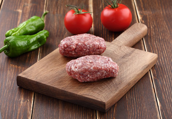 ground meat  with tomato and pepper on a wood background