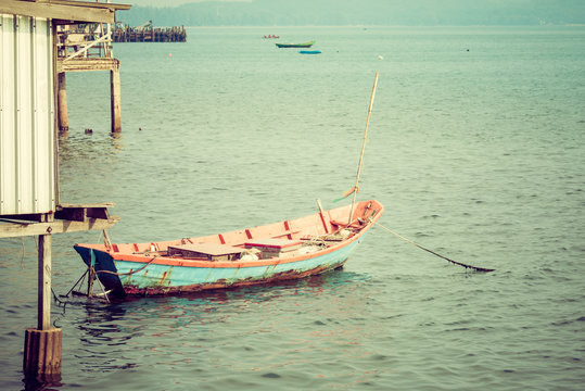 Fisherman boat floating at pier. Retro filter.