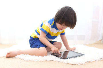 Little boy in striped t-shirt with tablet computer