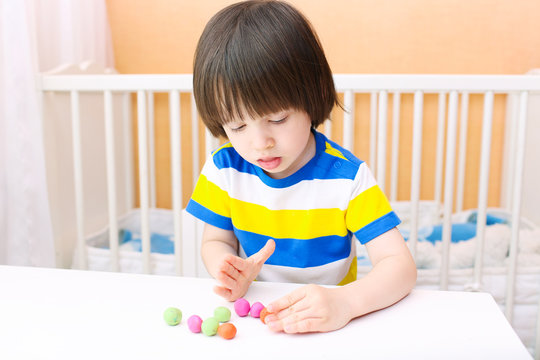 Little child modelling playdough balls