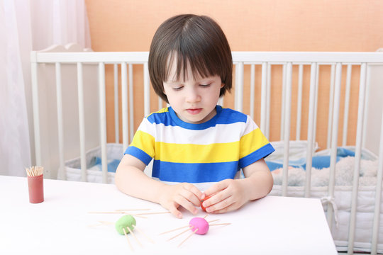 Portrait of cute little child making toothpick legs by playdough