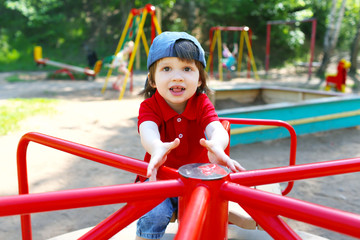 Fototapeta na wymiar Cute little boy on carrousel in summer