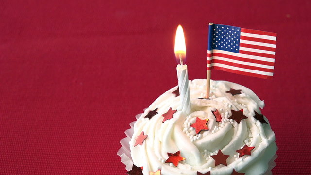 Birthday cupcake decorated with red stars and american flag with red background.  Flag is blown out.